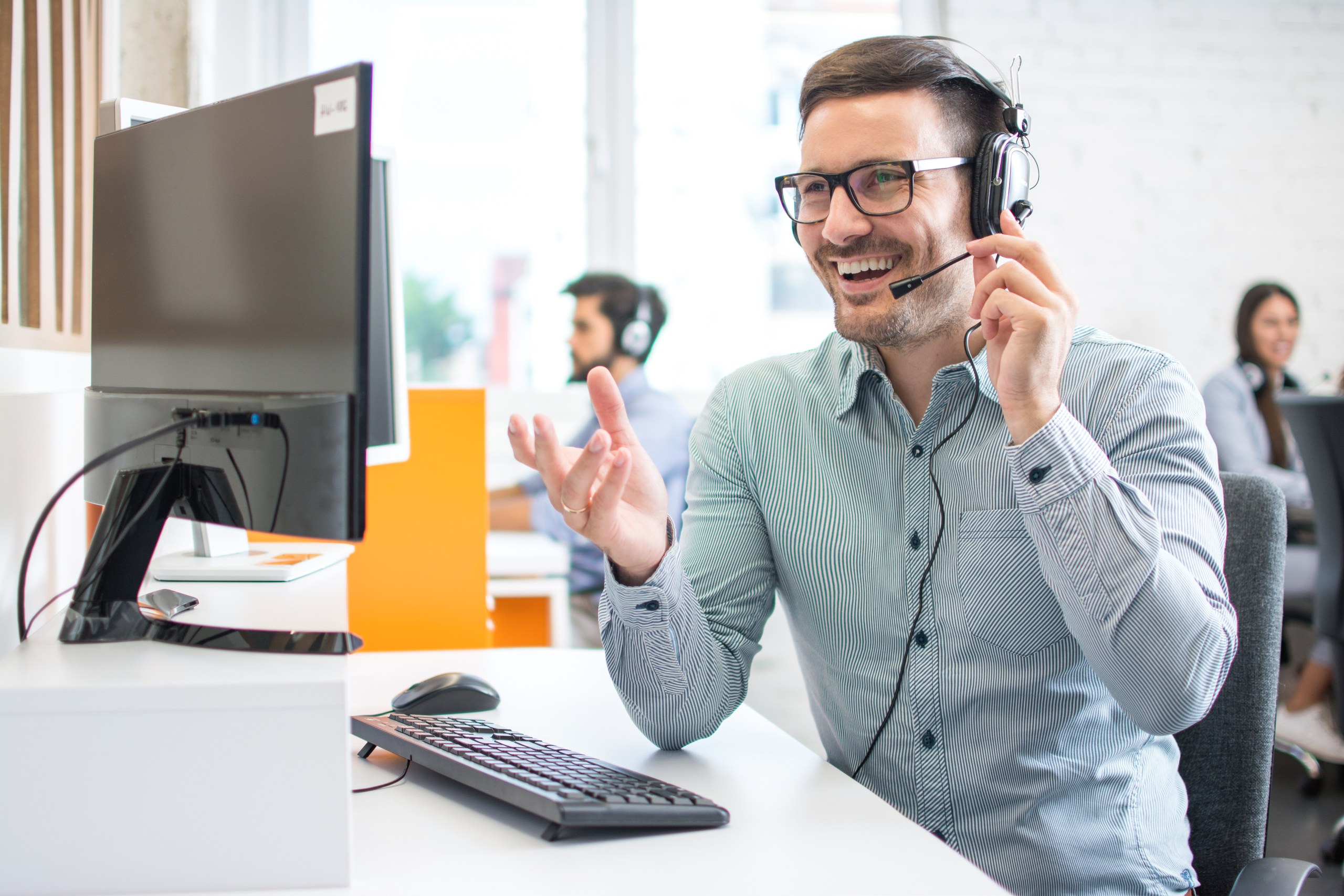 Happy handsome technical support operator with headset working in call centre